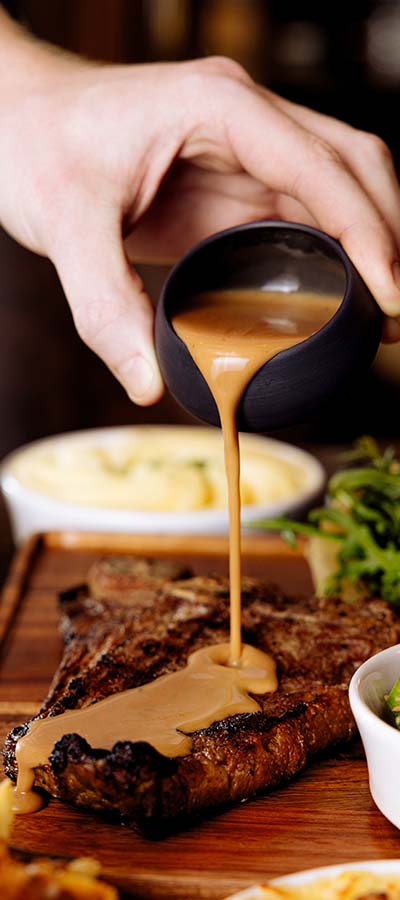Pouring pepper sauce on steak
